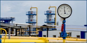 Photo of a yellow gas pipeline with additional equipment, pipes and a valve to cut off the gas supply. On a blurred background, an image of a gas compression station.